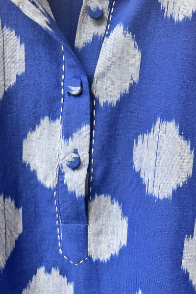 Close-up of a blue and gray ikat patterned shirt with covered cloth buttons.